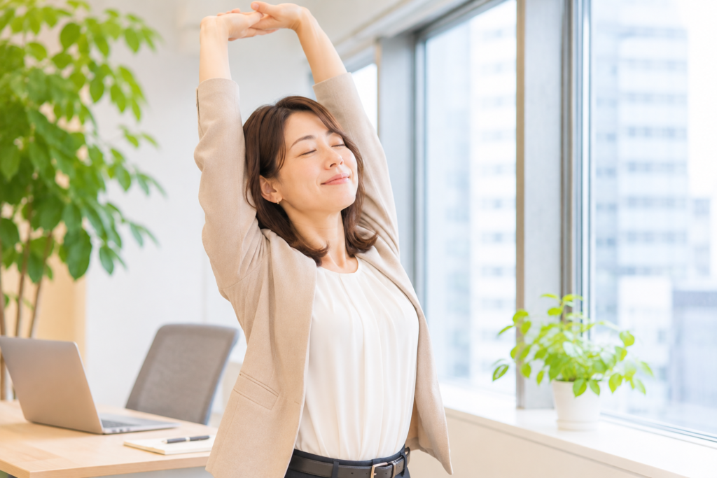 仕事の合間に伸びをする女性の画像